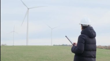 woman engineer with tablet  computer working in countryside with wind turbines