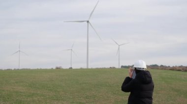 woman engineer with computer working in countryside with wind turbines