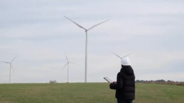 woman engineer with computer working in countryside with wind turbines