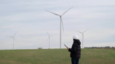 woman engineer with computer working in countryside with wind turbines