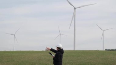 woman engineer with computer working in countryside with wind turbines