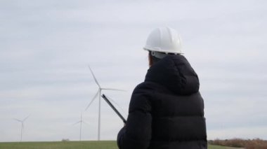 woman engineer with computer working in countryside with wind turbines