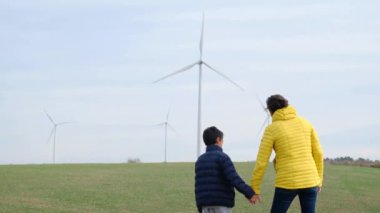 Anne ve oğlu kırsalda rüzgar türbinlerine bakıyor, ekoloji kavramı.
