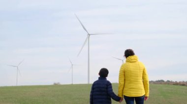 Anne ve oğlu kırsalda rüzgar türbinlerine bakıyor, ekoloji kavramı.