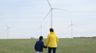 Anne ve oğlu kırsalda rüzgar türbinlerine bakıyor, ekoloji kavramı.