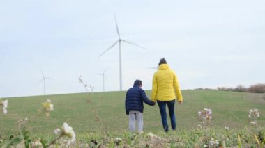 Anne ve oğlu kırsalda rüzgar türbinlerine bakıyor, ekoloji kavramı.