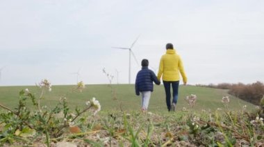 Anne ve oğlu kırsalda rüzgar türbinlerine bakıyor, ekoloji kavramı.