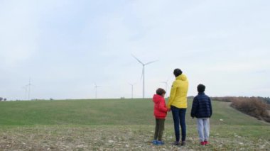 Anne ve oğulları kırsalda rüzgar türbinleri, ekoloji konsepti