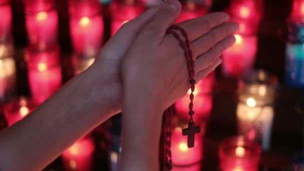一个人的手 一个女人在教堂里用十字架在蜡烛前祈祷 耶稣基督 对宗教和神的希望和信仰 对心灵的专注和内心的平静 — 图库视频影像