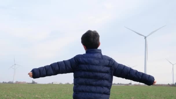 Menino Com Mãos Estendidas Campo Olhando Para Turbinas Eólicas Conceito — Vídeo de Stock