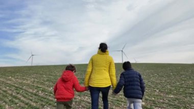 Oğulları olan bir anne kırsalda rüzgar türbinleriyle yürüyor, ekoloji kavramı.