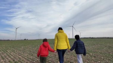 Oğulları olan bir anne kırsalda rüzgar türbinleriyle yürüyor, ekoloji kavramı.