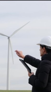 woman engineer with tablet  computer working in countryside with wind turbines