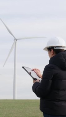 woman engineer with tablet  computer working in countryside with wind turbines