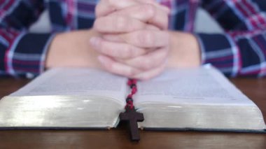 Genç bir kadın İncil ve haçla dua ediyor.