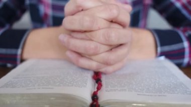 Genç bir kadın İncil ve haçla dua ediyor.