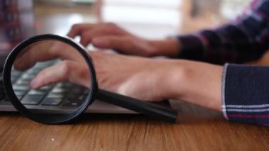 Dizüstü bilgisayar kullanan kişi. Büyüteç masanın üstünde. güvenlik kavramı