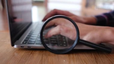 Dizüstü bilgisayar kullanan kişi. Büyüteç masanın üstünde. güvenlik kavramı