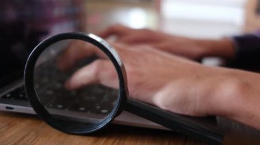 Dizüstü bilgisayar kullanan kişi. Büyüteç masanın üstünde. güvenlik kavramı