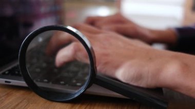 Dizüstü bilgisayar kullanan kişi. Büyüteç masanın üstünde. güvenlik kavramı