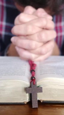 Genç bir kadın İncil ve haçla dua ediyor.