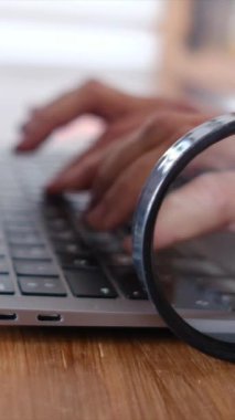 Dizüstü bilgisayar kullanan kişi. Büyüteç masanın üstünde. güvenlik kavramı