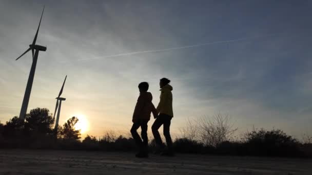 日落时分带着儿子在农村走向风力涡轮机的年轻母亲 生态概念 — 图库视频影像