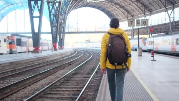 鉄道駅のプラットホームを歩いているバックパックと若い女性旅行者 — ストック動画