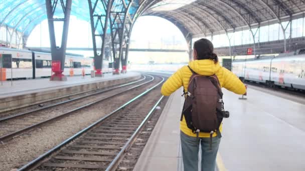 バックパック付きの若い女性旅行者は プラットフォーム上の列車を待っています — ストック動画