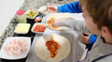 İki çocuk mutfakta lezzetli pizzalar hazırlıyor.