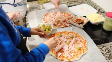 İki çocuk mutfakta lezzetli pizzalar hazırlıyor.
