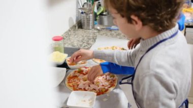 İki çocuk mutfakta lezzetli pizzalar hazırlıyor.