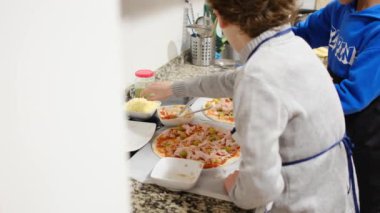 İki çocuk mutfakta lezzetli pizzalar hazırlıyor.