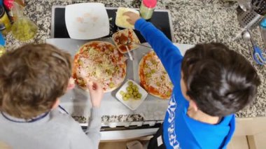 İki çocuk mutfakta lezzetli pizzalar hazırlıyor.