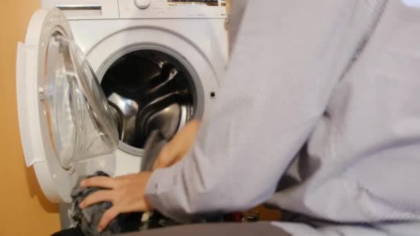 洗濯機で子供の服を洗っている男 ジェンダーと国内の仕事の概念を破り 平等と自宅の男性を家族と妻に助ける — ストック動画