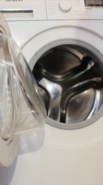 Çamaşır makinesine çamaşır koyan adam.