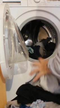 Adam otomatik çamaşır makinesinden giysileri çıkarıyor..