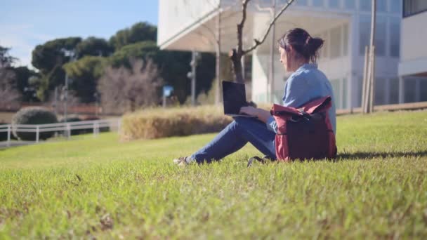 彼女のラップトップとキャンパスで勉強することに没頭した大学の学生は 彼女のEラーニングの旅に自信を持って屋外の静けさを受け入れます — ストック動画