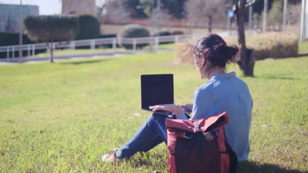年轻女子坐在公园里 使用现代笔记本电脑 自由职业者的远程工作 具有行动和金融自由的创造性专业人员 — 图库视频影像