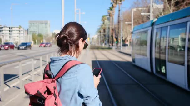 年轻女子使用智能手机白色等待车站在白天 幸福的城市生活冒险 — 图库视频影像