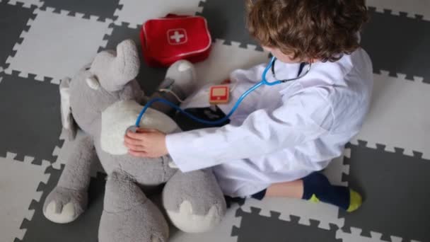 Kleiner Junge Arztkittel Mit Stethoskop Spielt Mit Spielzeug Elefant — Stockvideo