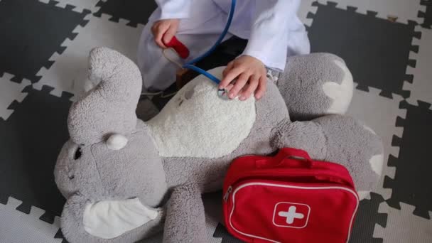 Kleiner Junge Arztkittel Mit Stethoskop Spielt Mit Spielzeug Elefant — Stockvideo