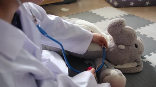 おもちゃの象と遊ぶステスコープで医療服を着ている小さな少年 — ストック動画