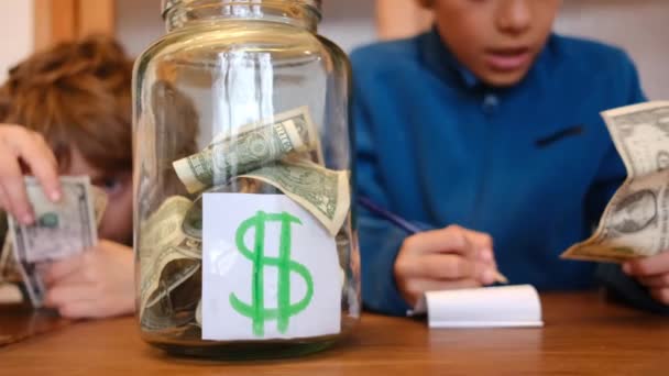 Маленькі Хлопчики Збирають Доларові Банкноти Банці Економії Сидячи Дерев Яним — стокове відео