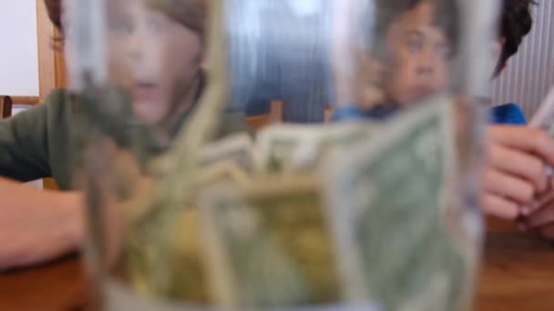 Маленькие Мальчики Собирают Долларовые Банкноты Банку Экономии Сидя Деревянным Столом — стоковое видео