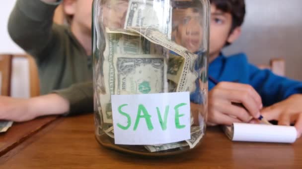 Маленькі Хлопчики Збирають Доларові Банкноти Банці Економії Сидячи Дерев Яним — стокове відео
