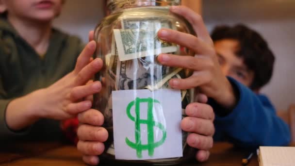 Kleine Jongens Verzamelen Dollarbiljetten Potje Sparen Terwijl Aan Houten Tafel — Stockvideo