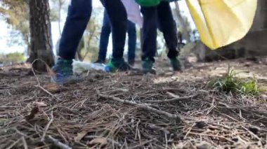 Anne ve oğulları güneşli bahar gününde doğada çöp topluyorlar.