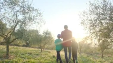 Anne ve oğulları güneşli bahar gününde meyve bahçesini kontrol ediyorlar.