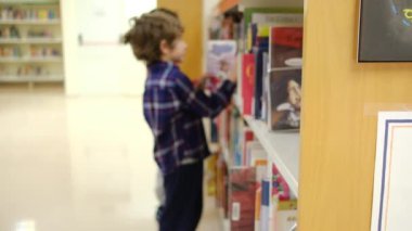 Küçük çocuklar kütüphanede kitap seçiyor.